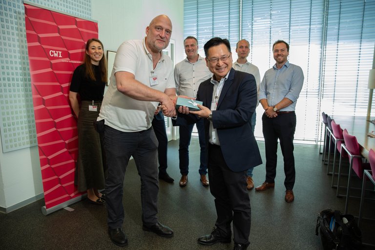 Prof. Ronald Cramer (CWI, UL) handing over a present to Prof. LAM, Kwok Yan (NTU), 8 June 2023