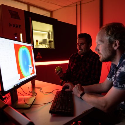 Tristan van Leeuwen sitting in front of a computer, studying the x ray image of the inside of an apple