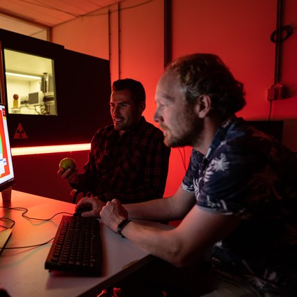 Tristan van Leeuwen sitting in front of a computer, studying the x ray image of the inside of an apple