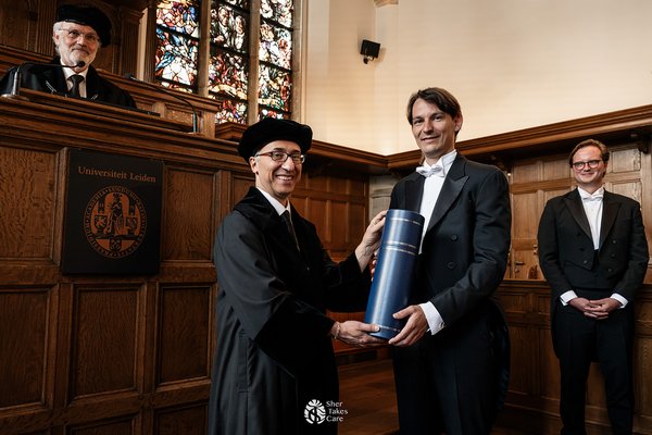 Hans-Dieter Hiep (CWI and Leiden University) outside the CWI building, with a network builduing in the background.
